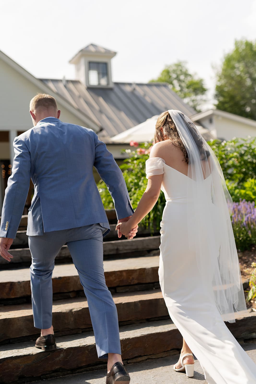 couple holding hands and walking up the steps on a sunny day