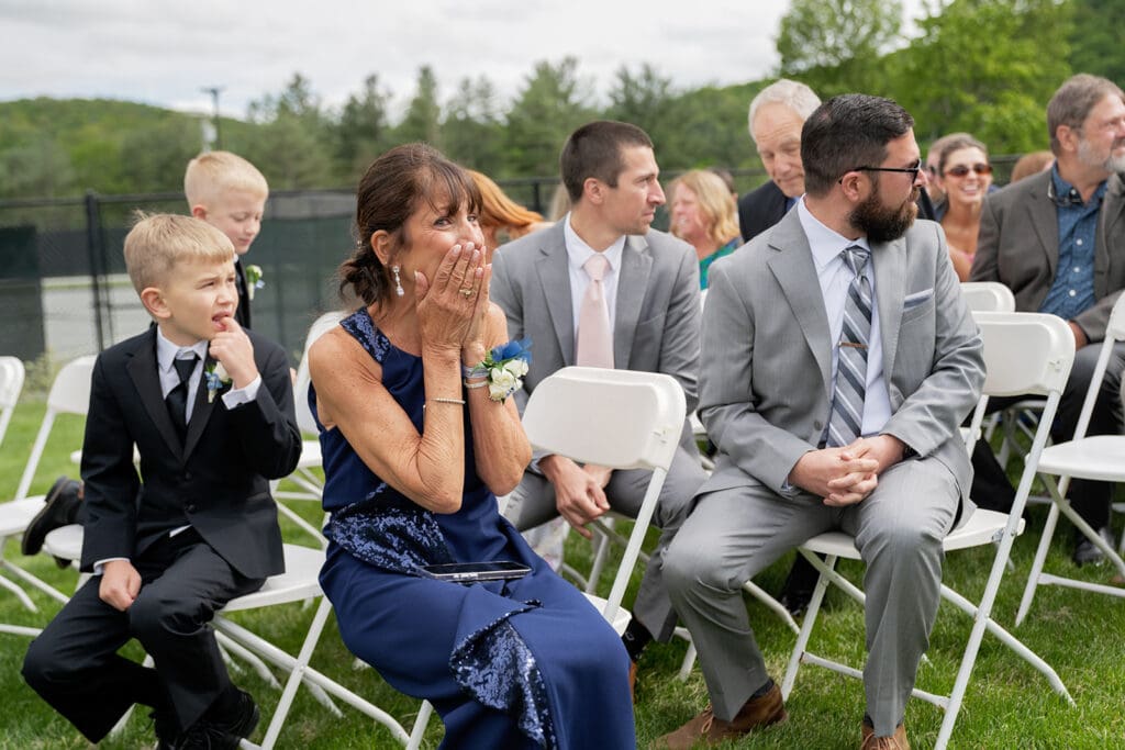 woman in blue dress crying as bride walks down the aisle