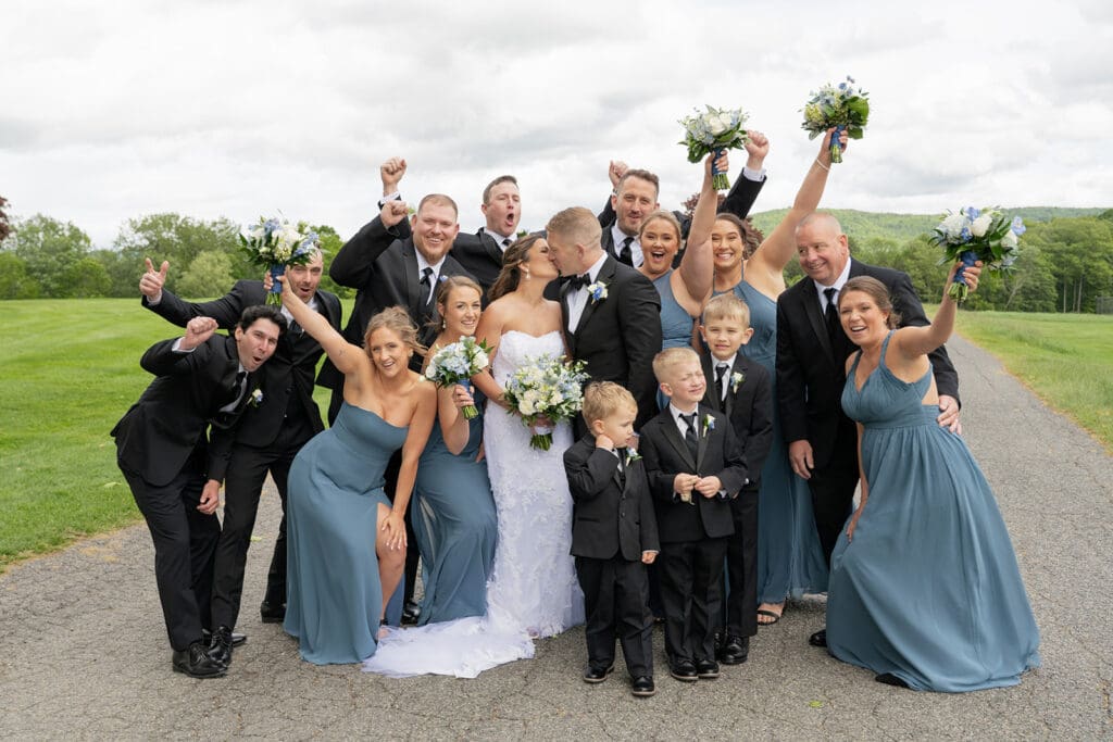 bridal party cheering while bride and groom kiss