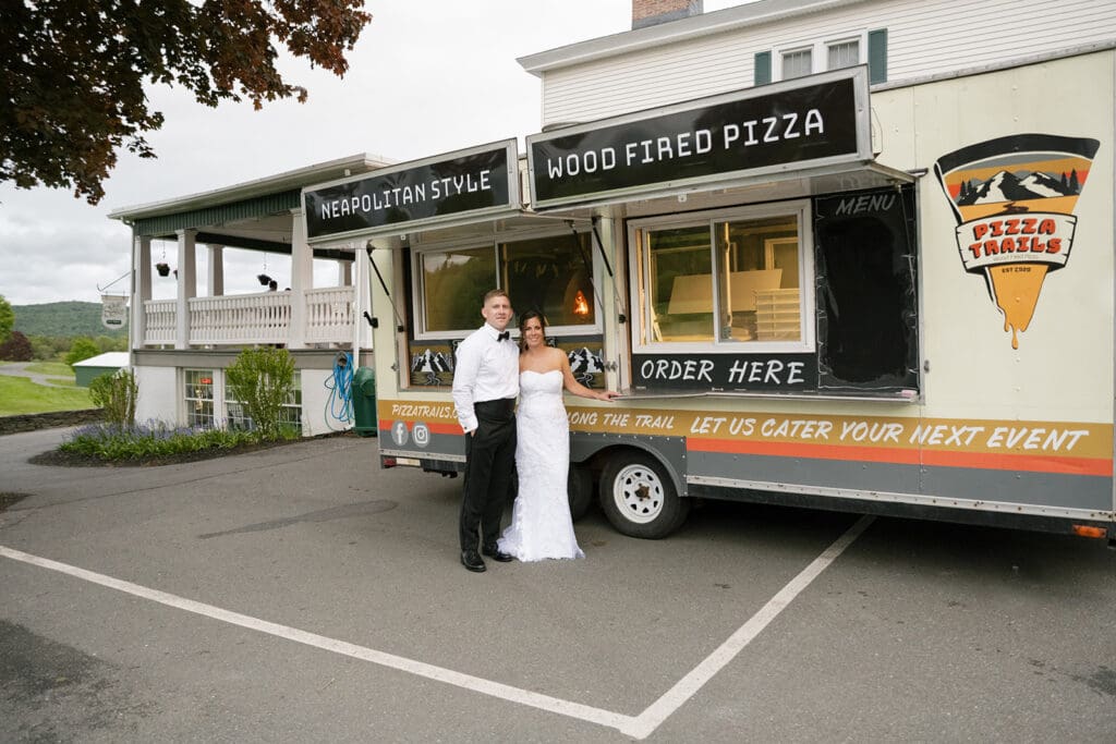 couple posing in front of a pizza truck on their wedding day