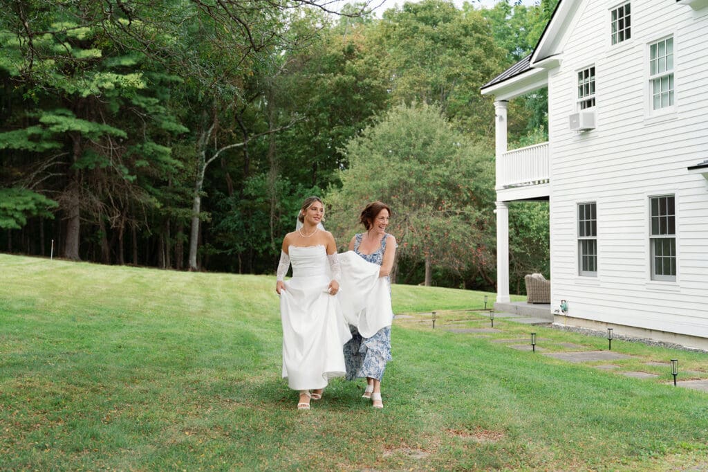mom carries bride's train as she walks towards the camera