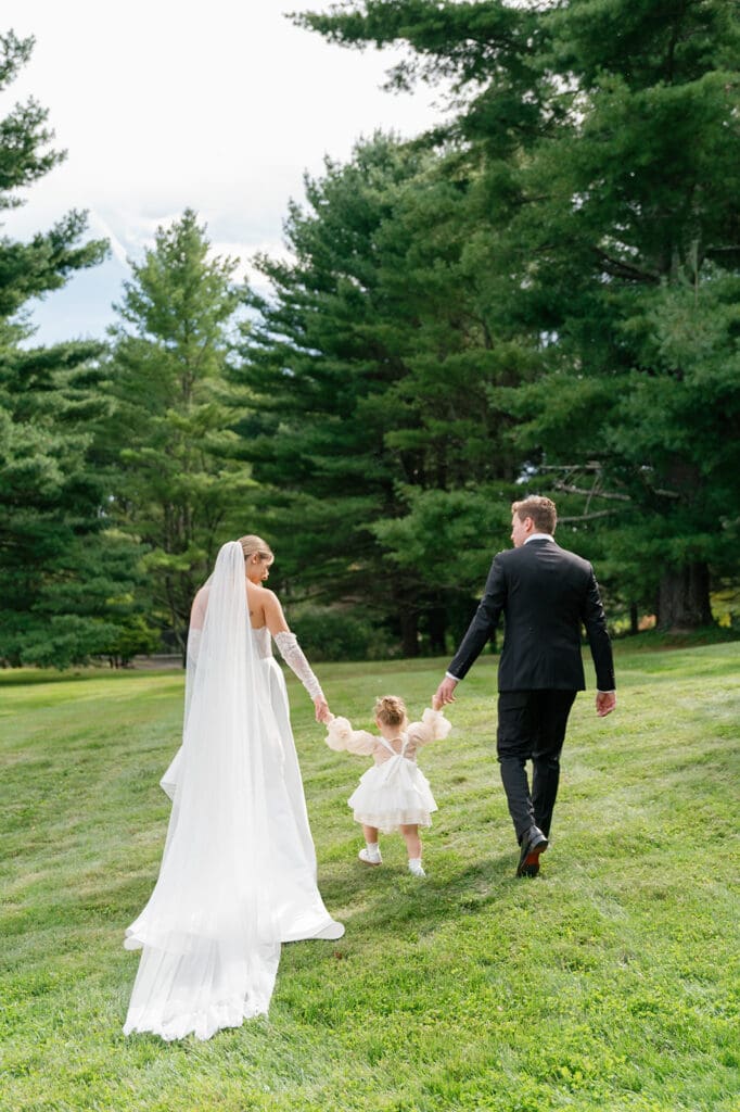 bride, groom, and toddler holding hands walking away