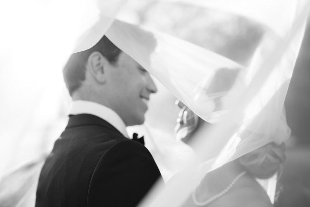 black and white photo of bride and groom under the veil