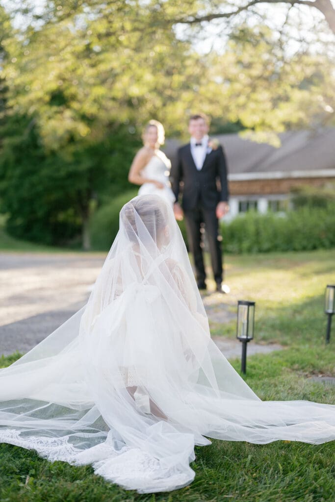 flower girl under the bride's veil with bride and groom laughing in the background