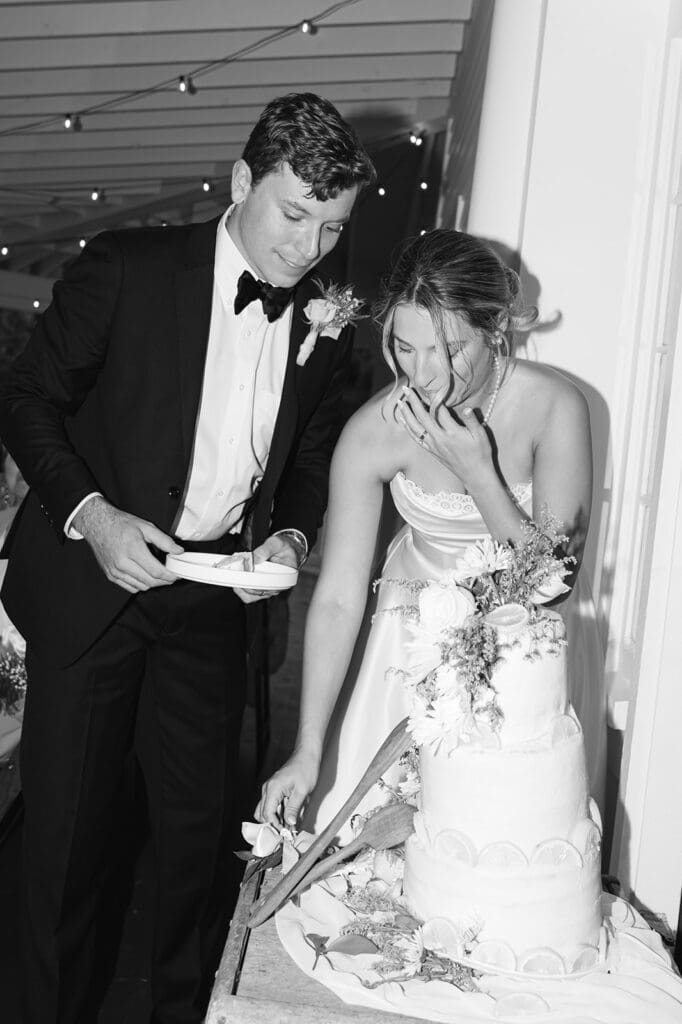 black and white photo with flash of bride and groom joyfully cutting their cake