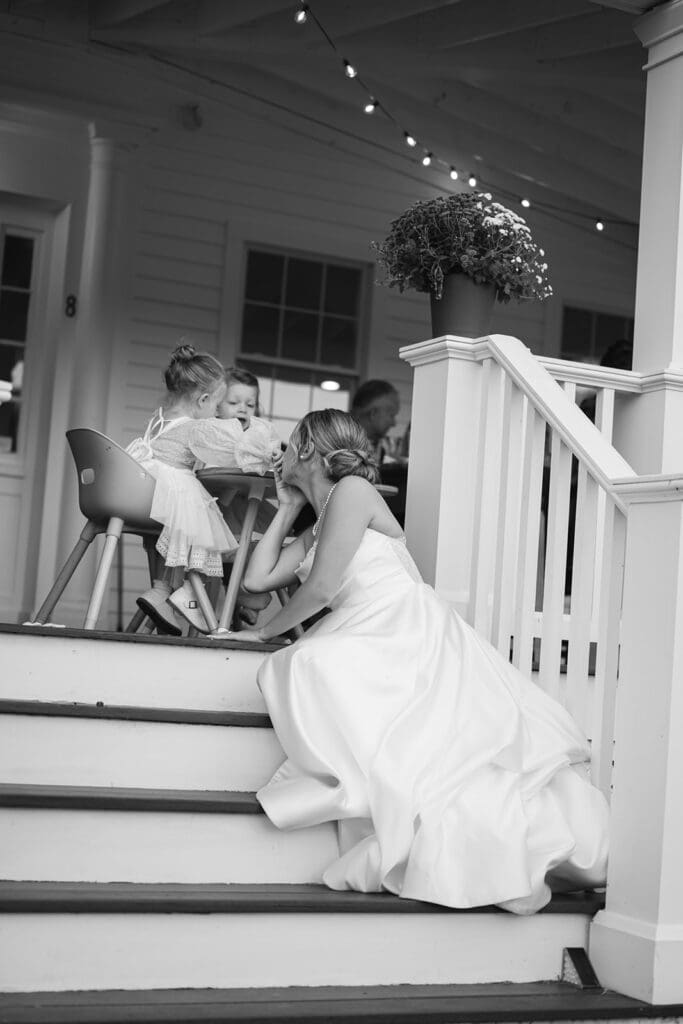 black and white photo of bride sitting on steps playing with toddler